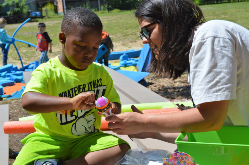 young child interacts outside with Knock Knock volunteers.