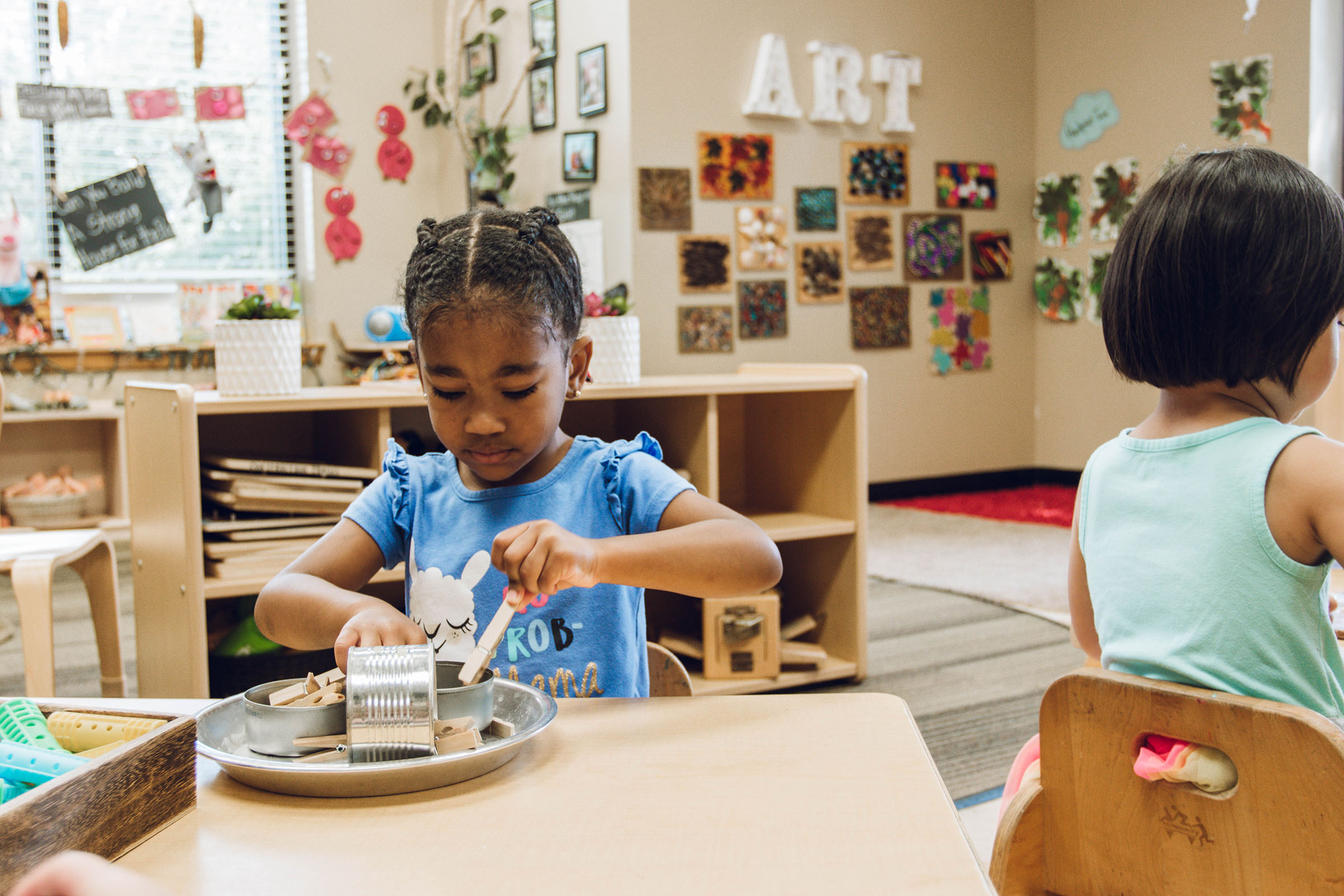 Black girl playing with manipulatives at table in a preschool classroom