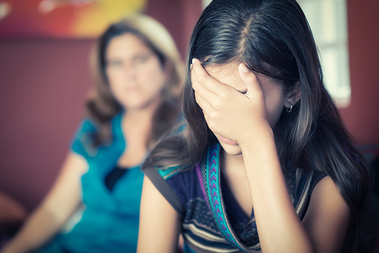 photo of sad girl with mom in background