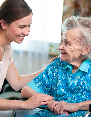 Photo of a young caregiver assisting an older woamn in a wheelchair